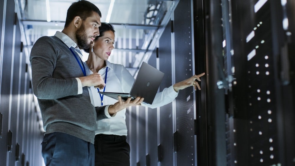 Kiwa experts, a woman and a man, looking at computer servers